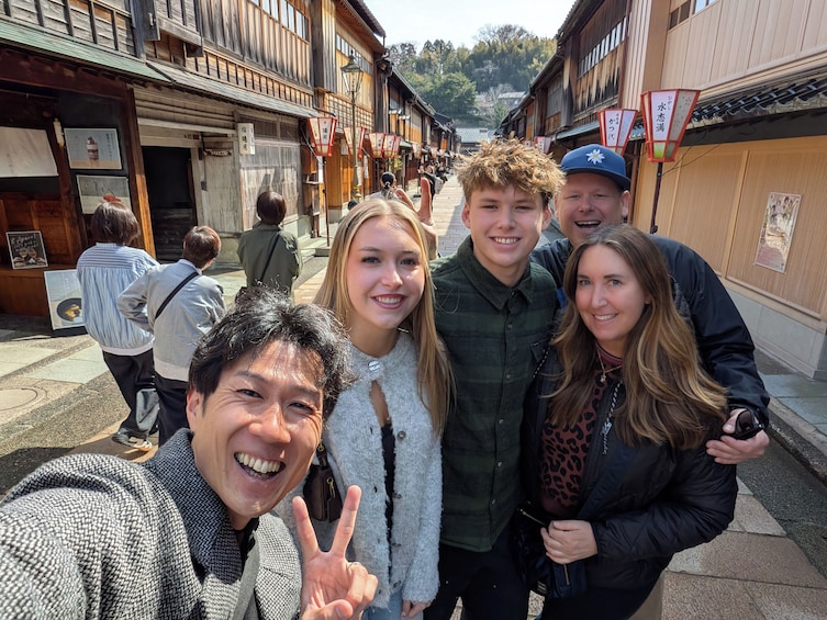 A group of people standing in a narrow street with traditional wooden buildings on either side. 2