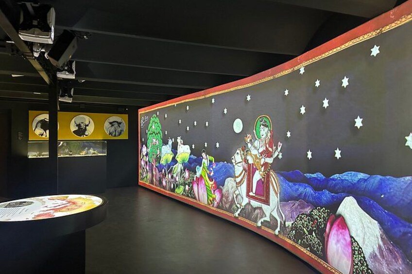 Una exhibición de museo con un gran mural de una escena nocturna, que incluye una figura a caballo y estrellas. 2