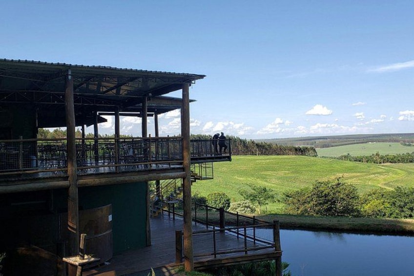 A wooden structure with a balcony overlooking a body of water and a green landscape. 5