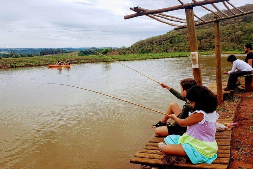 People fishing by a river, wooden dock, and a distant boat. 3