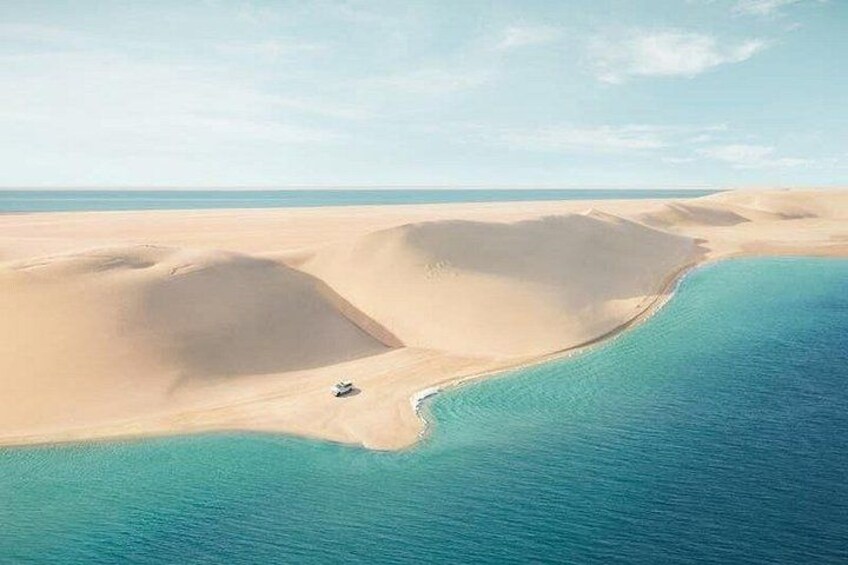 Paisaje desértico con dunas de arena y una masa de agua. 2
