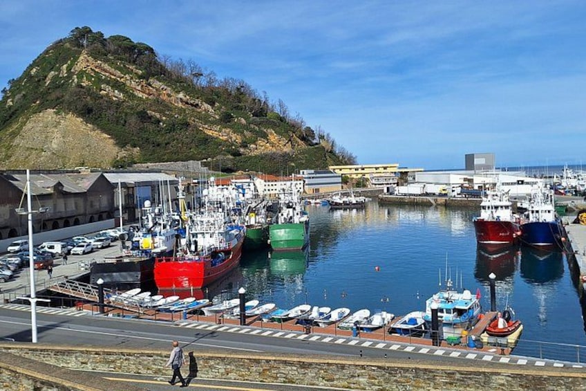 A harbor with boats, a dock, and a hilly landscape. 2