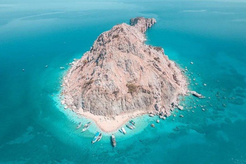Een luchtend uitzicht op een rotsachtig eiland, omringd door turquoise water. 1