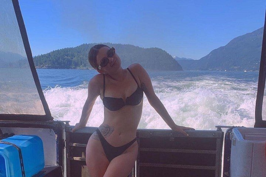 A person in a bikini on a boat with a mountainous landscape in the background. 2