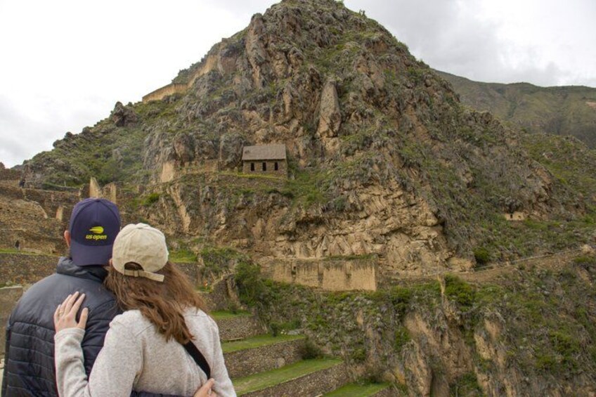 Una coppia in piedi su un pendio roccioso con vista su rovine antiche. 3