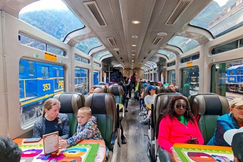 Interno di un treno con passeggeri seduti, finestrini che mostrano un paesaggio montuoso e il numero del treno 353. 5