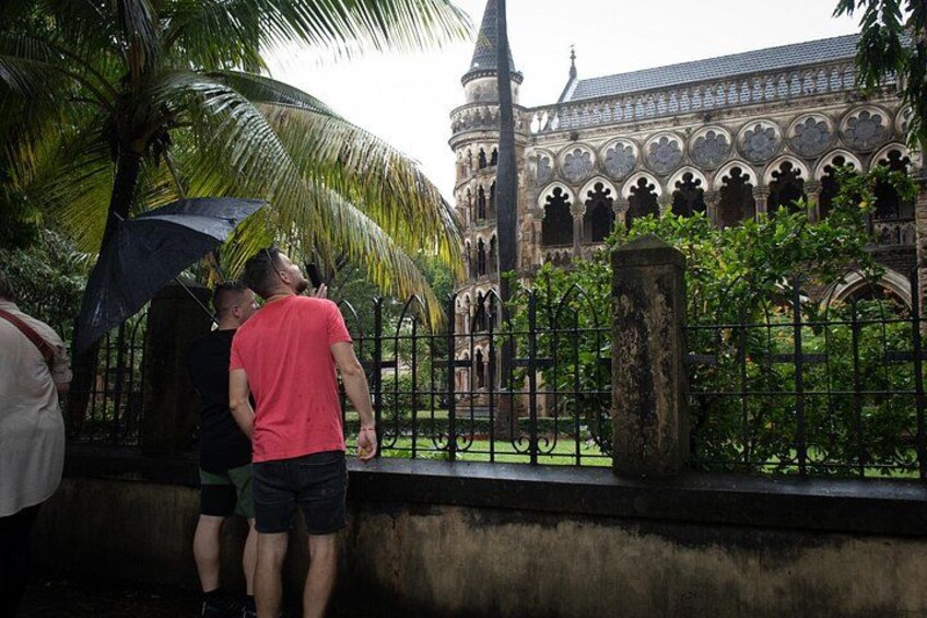 A historic building with intricate architecture, a palm tree, and a person holding an umbrella. 4