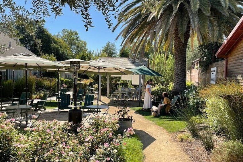 A patio with outdoor seating, a palm tree, and a garden with pink flowers. 2