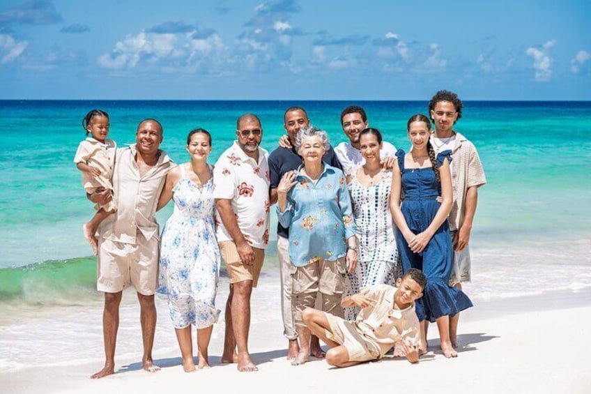 A family of nine on a beach with clear turquoise water and a white sandy shore. 4