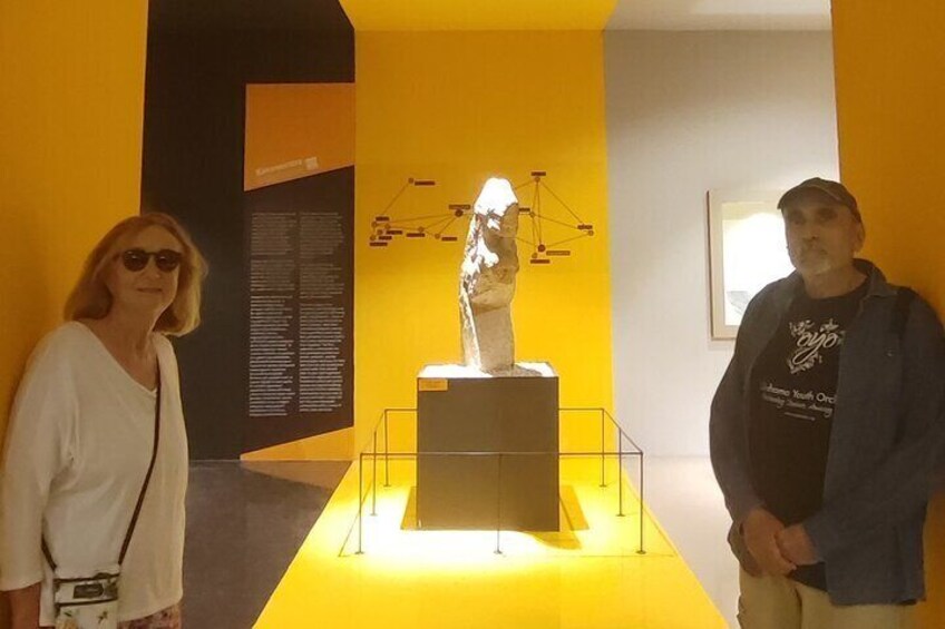 Two people standing in front of a sculpture in a gallery with yellow walls. 4