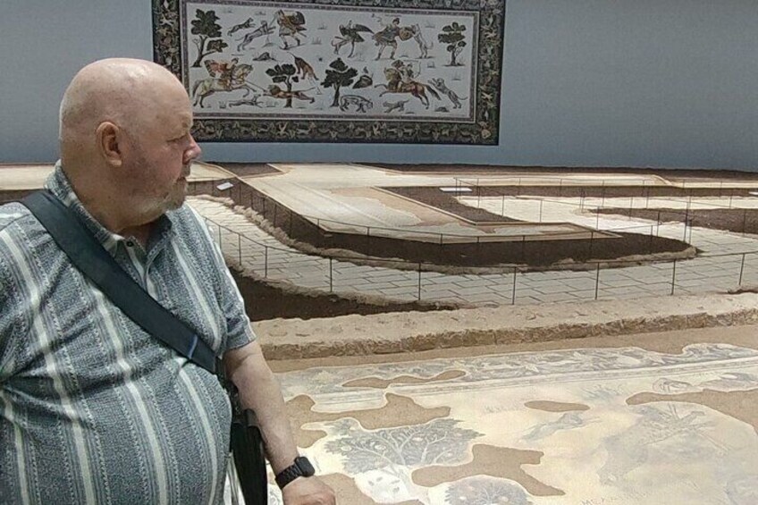 A man standing in front of a mosaic with a patterned floor in the background. 5