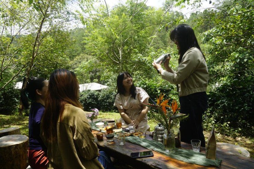 A group of people sitting at an outdoor table with drinks and a plant. 3