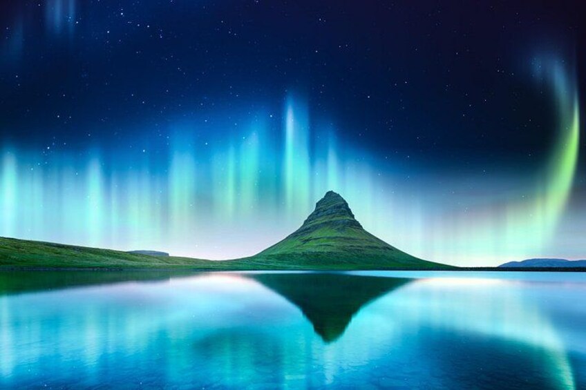 A mountain with a lake in front, and the sky is filled with auroras. 4
