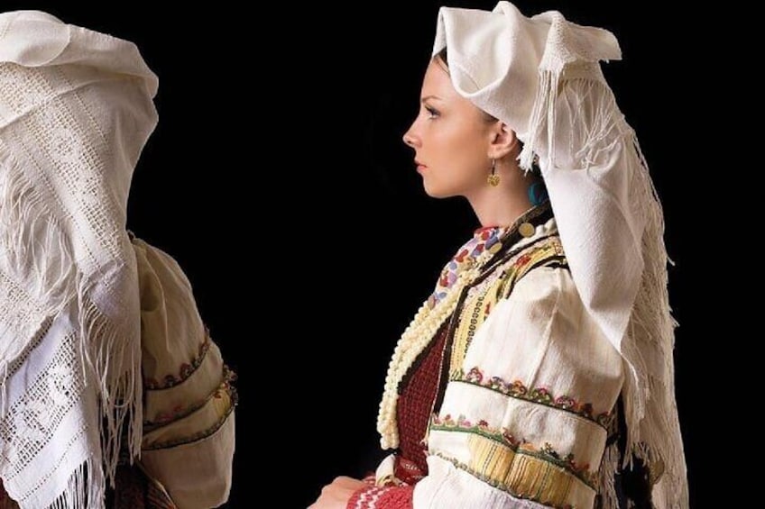 A person in traditional attire with a white headscarf and a patterned garment. 5