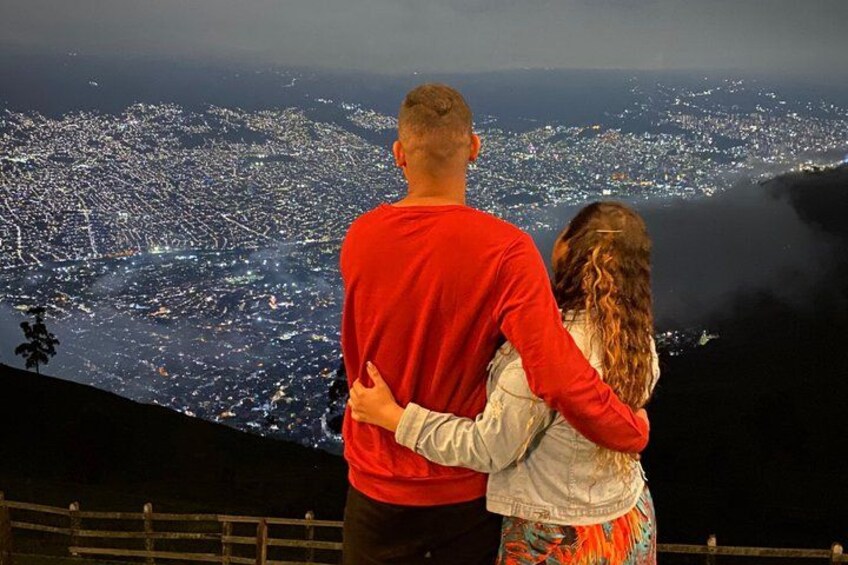 A couple embracing, overlooking a cityscape at night. 1