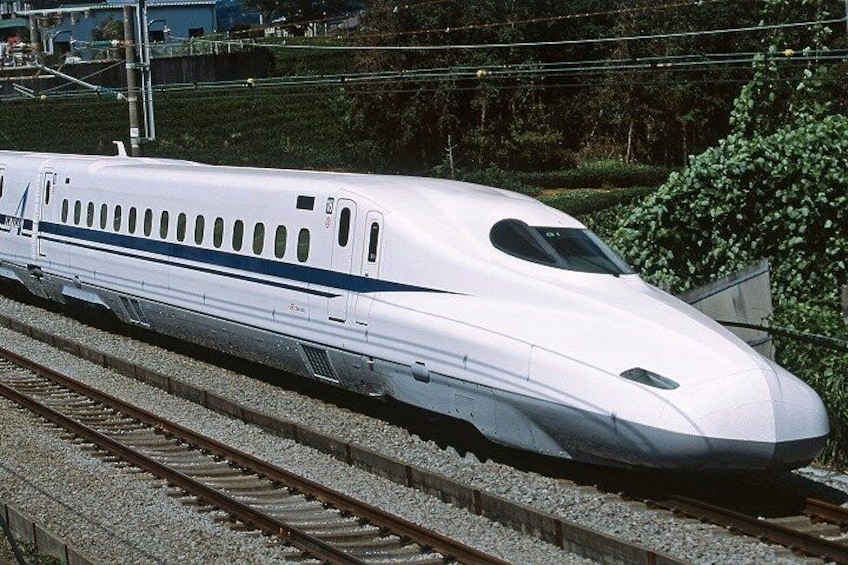 A high-speed train on tracks with a streamlined design, surrounded by greenery and infrastructure. 4