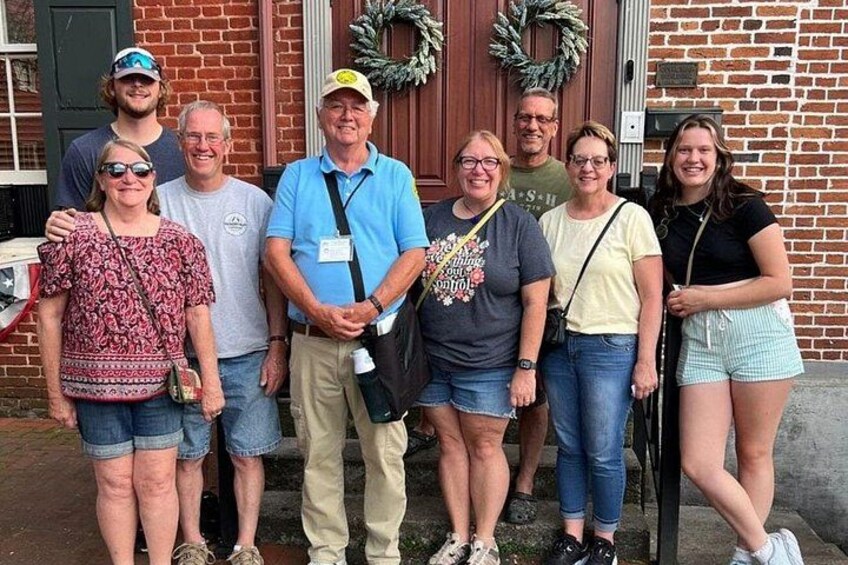 A group of people standing in front of a brick building with a wreath on the door. 2