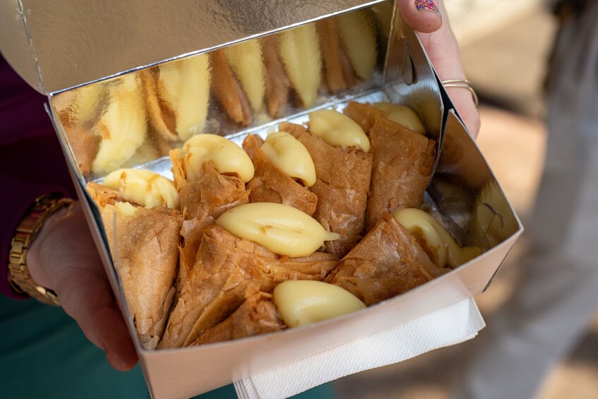 A person holding a box containing pastries. 2