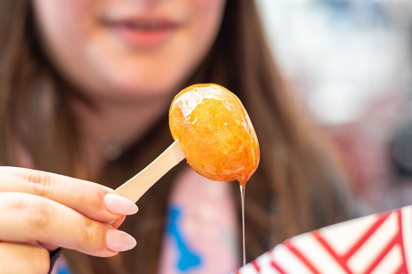 A person holding a lollipop with a wooden stick. 4
