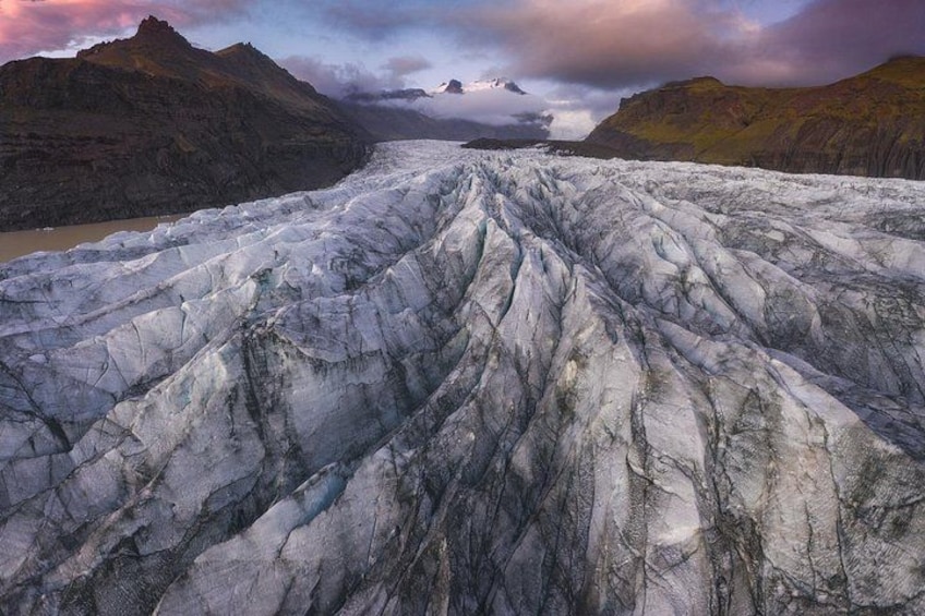 A glacier stretches across the land with thick ice, cracks, and uneven surfaces. 5