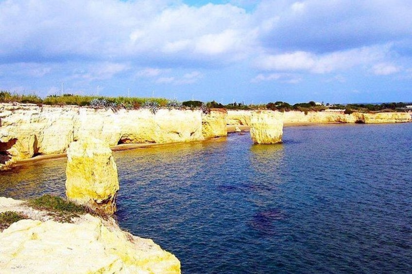 A coastal landscape with prominent white rock formations and calm blue waters. 2
