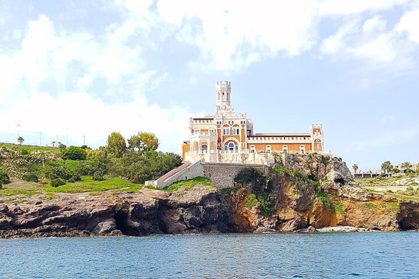A historic building with a tower, situated on a rocky coastline. 4