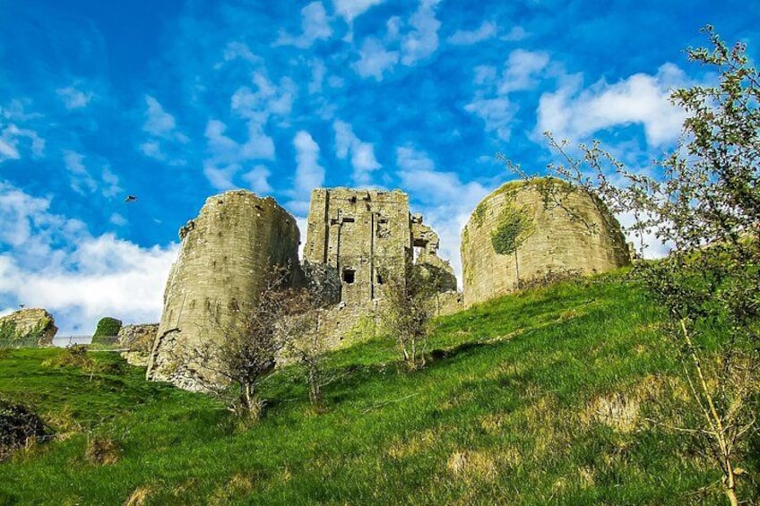 A historic stone castle ruin on a grassy hill with a clear blue sky. 5