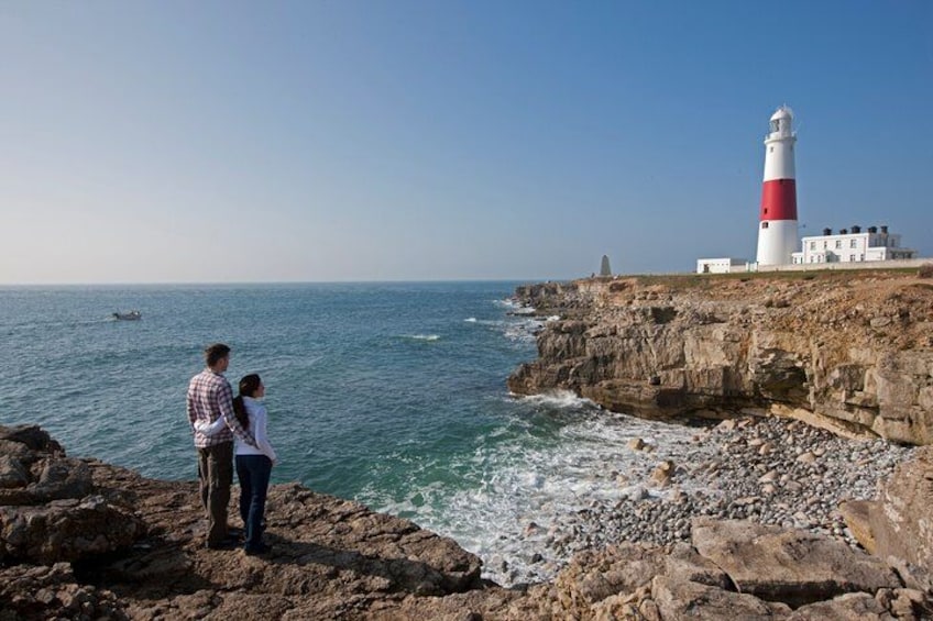 A lighthouse, rocky coastline, and a couple standing on the rocks. 3