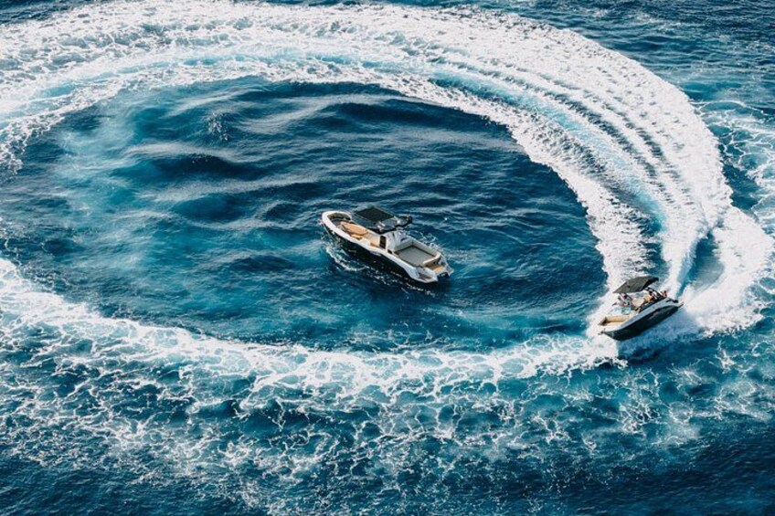 Two boats creating a circular wake pattern in the ocean. 5
