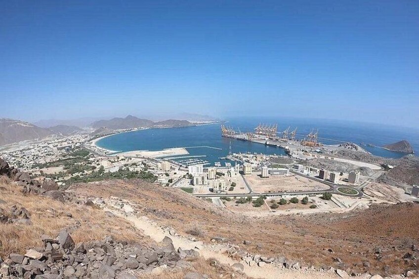 A coastal city with a large port, buildings, and a hilly landscape. 3