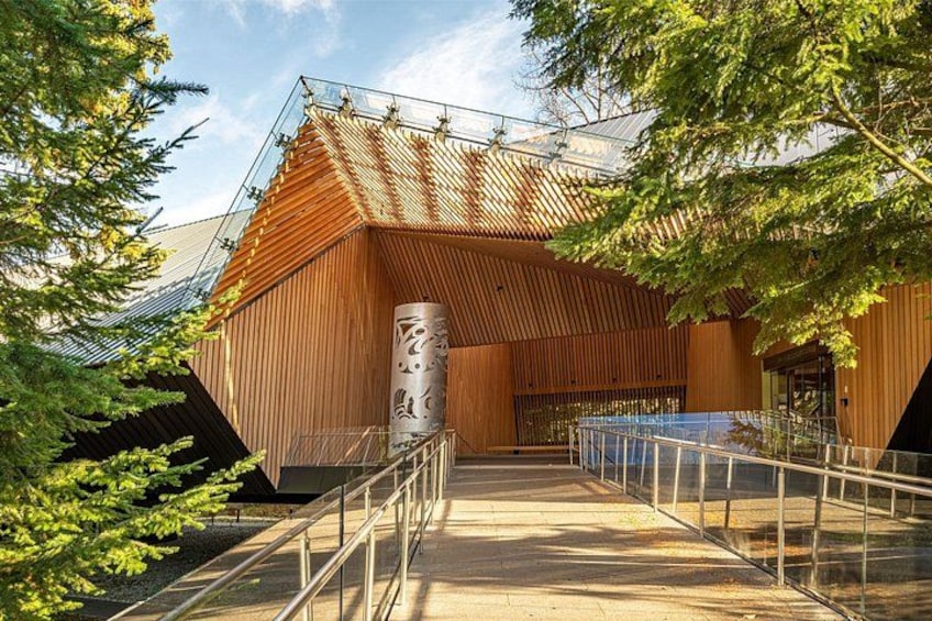 A modern building with a sloped roof, surrounded by trees. 3