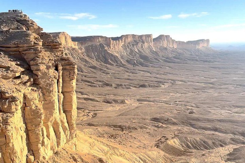 A vast desert landscape with prominent rock formations and a clear sky. 3