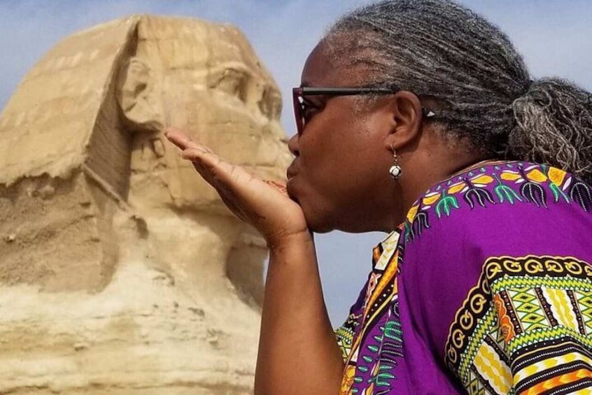 A person in a colorful garment standing in front of a large sand sculpture. 2