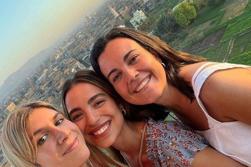 Three people taking a selfie with a cityscape in the background. 3