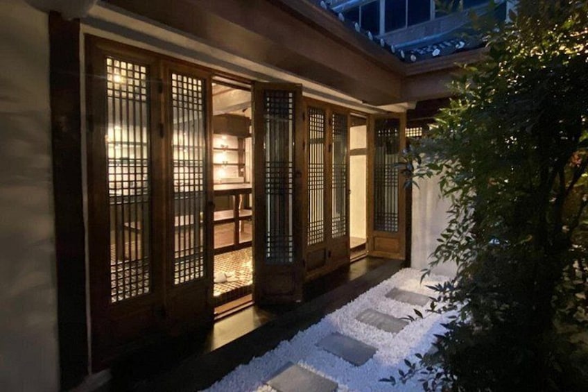 A traditional Japanese gate with illuminated interiors, a stone pathway, and a small tree. 4