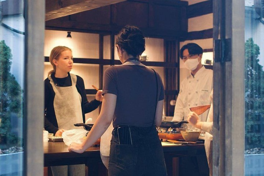 A person in a chef's uniform cooking at a kitchen counter. 2