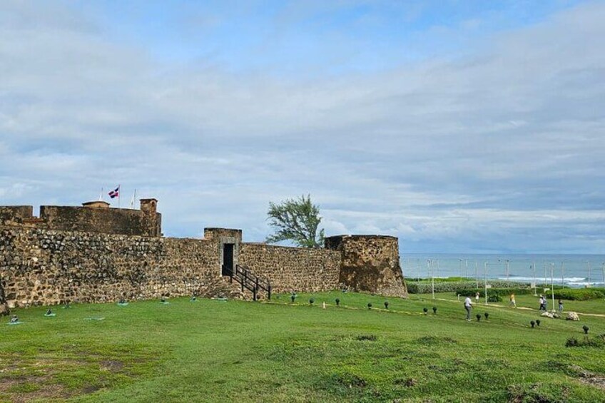 A stone fort with a grassy field in the foreground and a body of water in the background. 5