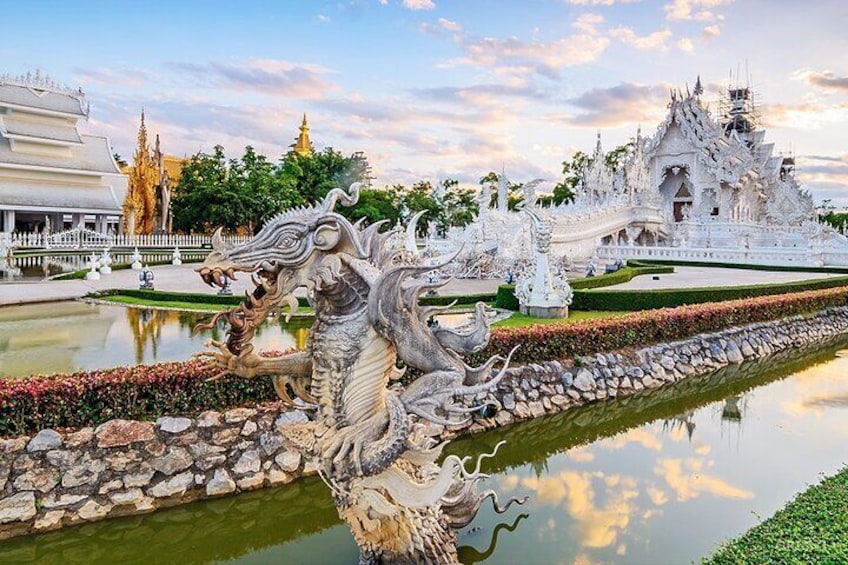 A white ornate temple complex with a dragon statue in the foreground. 1