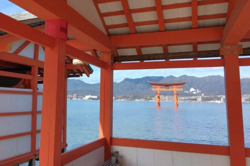 Un tradizionale torii giapponese immerso nell'acqua, struttura in legno con parte superiore incurvata, visto da un'area coperta con pilastri rossi. 3