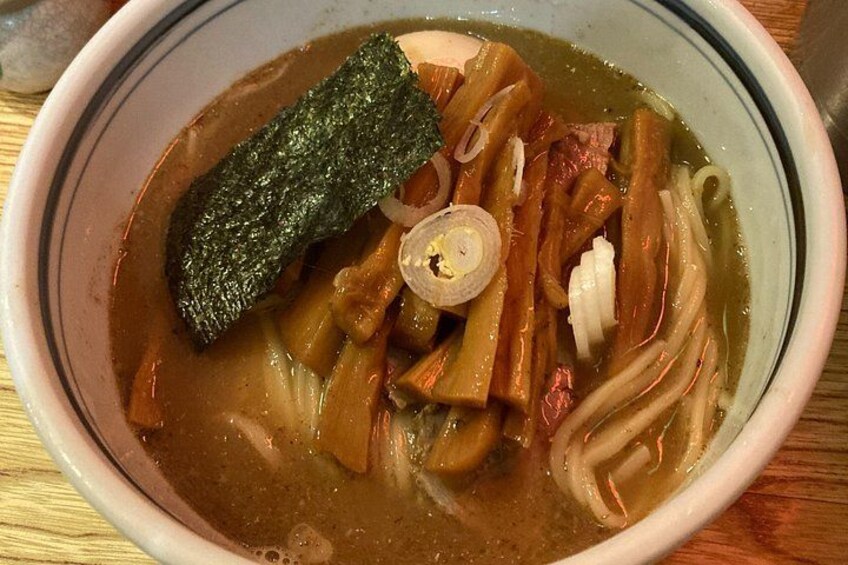 Un tazón de sopa con fideos, cebolla en rodajas y algas. 3