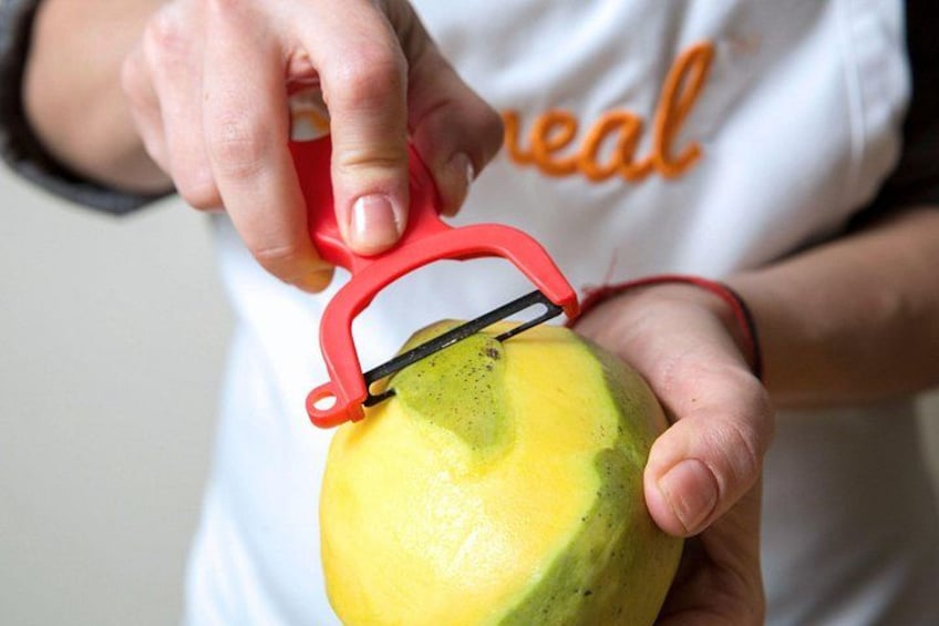 A person using a red tool to cut a yellow fruit. 2