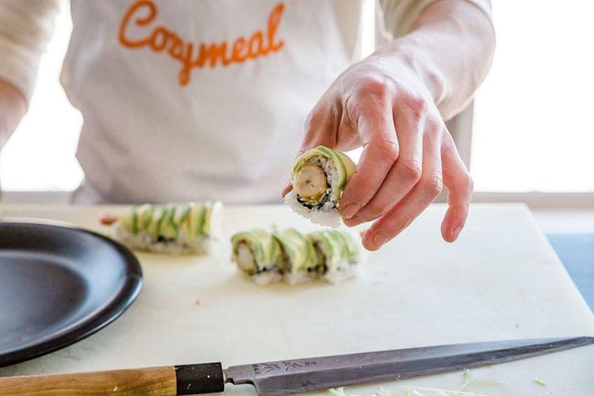 A person preparing sushi rolls on a cutting board. 5