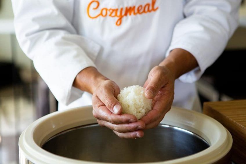 A person holding a rice ball over a slow cooker. 4