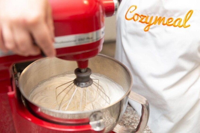 A person using a red KitchenAid mixer to blend ingredients in a metal bowl. 5