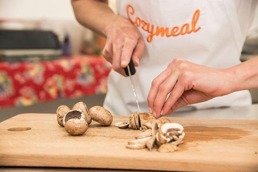 A person cutting mushrooms on a wooden cutting board. 4