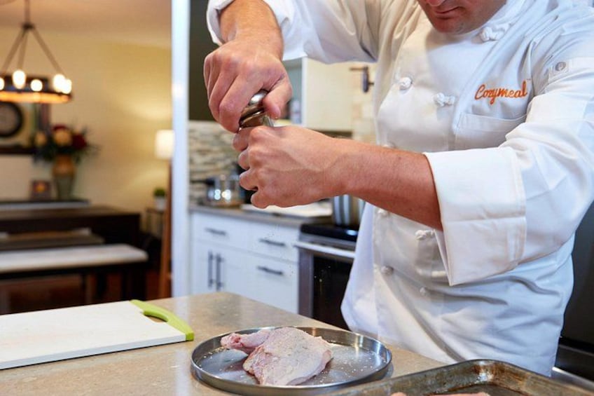 A chef in a white uniform with 'Coxmeal' on the chest, preparing food in a kitchen. 3