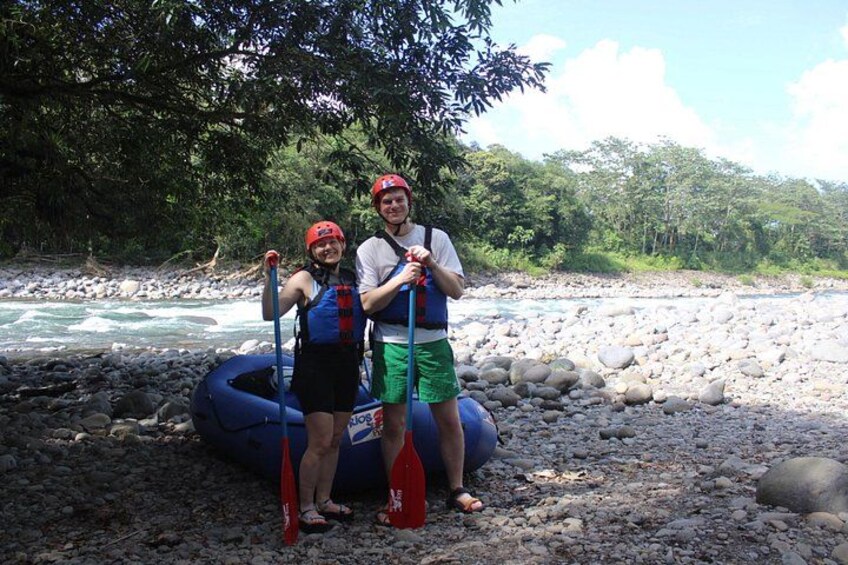 Twee personen staan bij een rivier met een vlot en peddels. 4