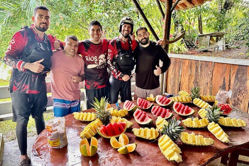 Een groep mensen staat rond een tafel met gesneden fruit. 2