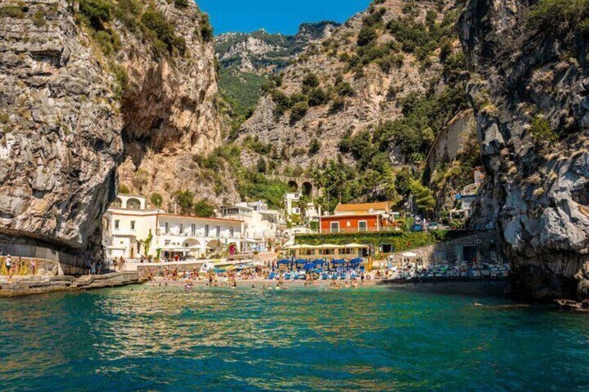 A coastal town with buildings, a beach, and rocky cliffs. 2
