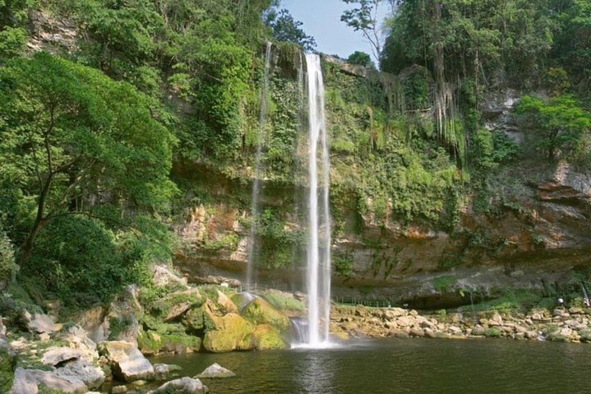 A waterfall cascading into a river surrounded by lush greenery and rocky terrain. 2